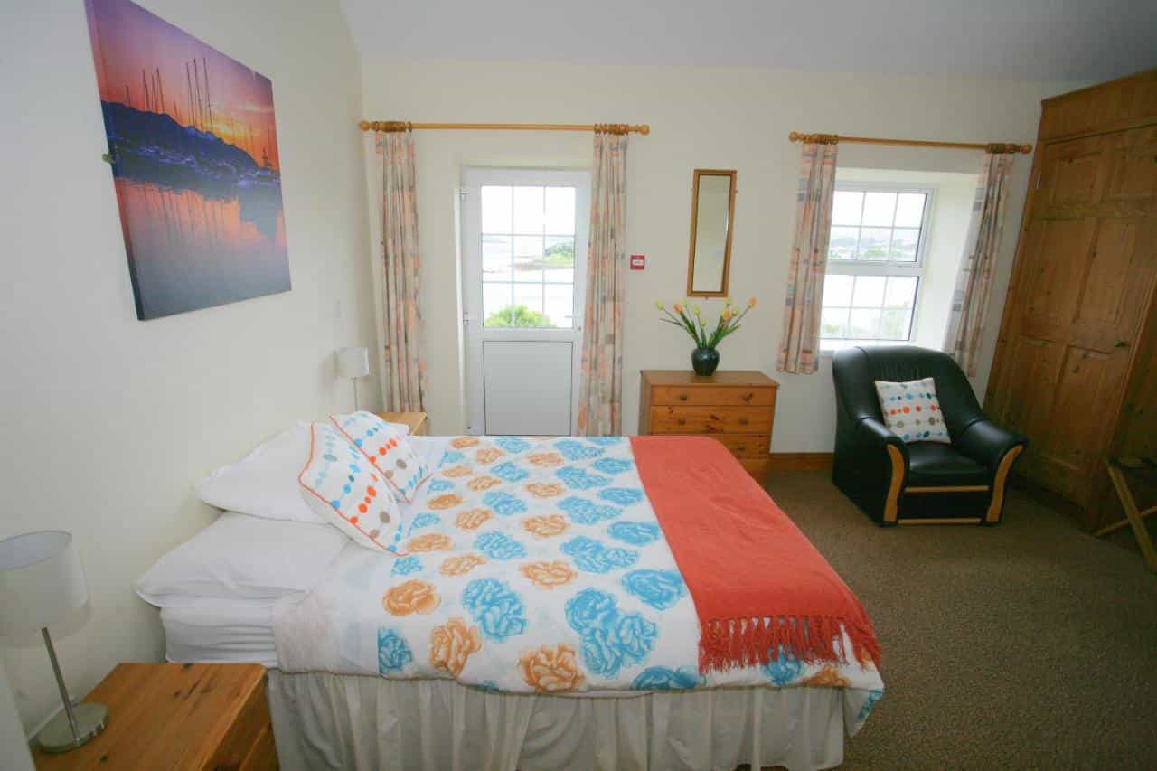Bedroom at Cottage Heights with floral duvet and view of water outside door.
