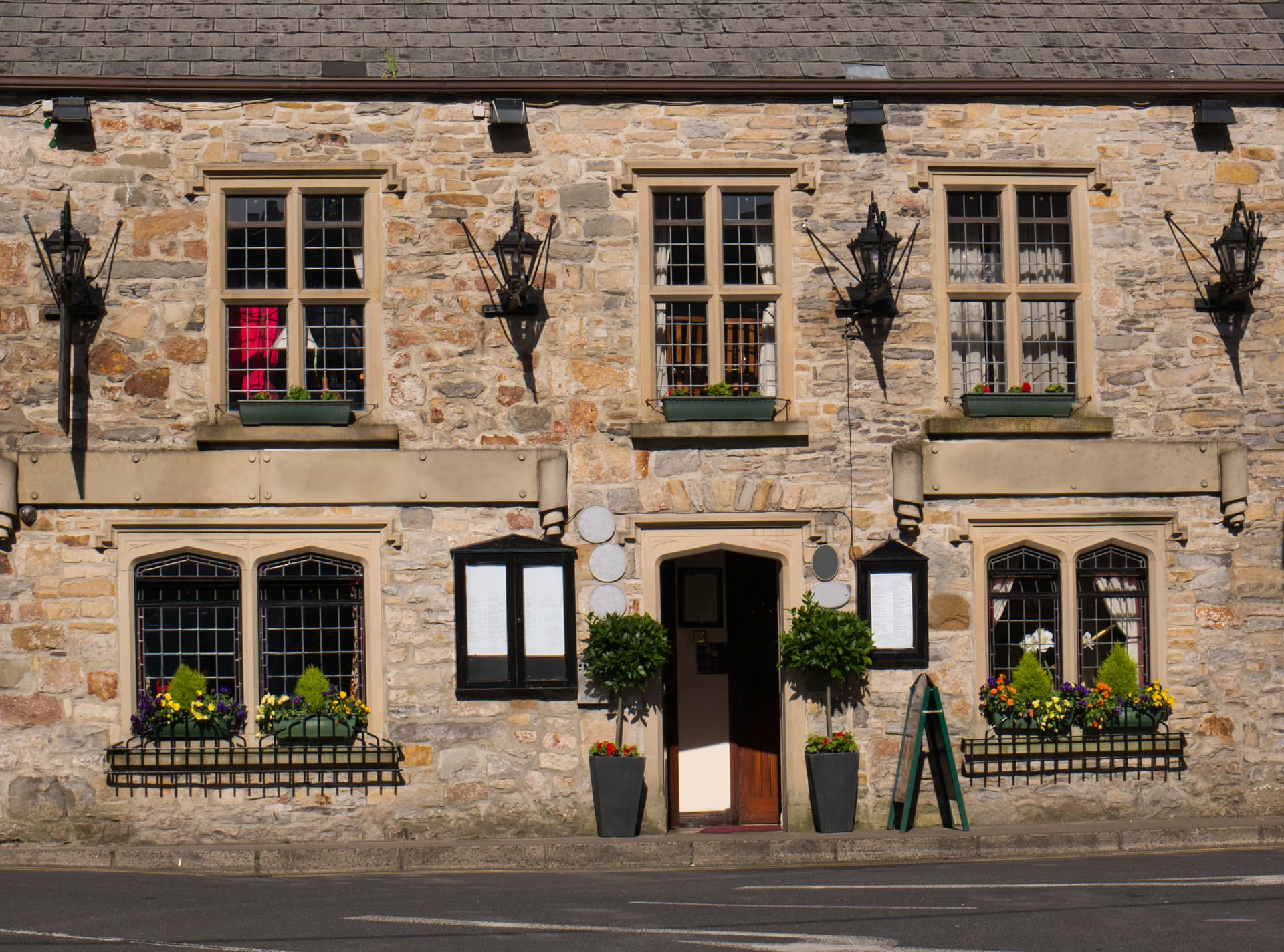 Stone building facade with multiple windows, flower boxes, and decorative lanterns in Donegal.