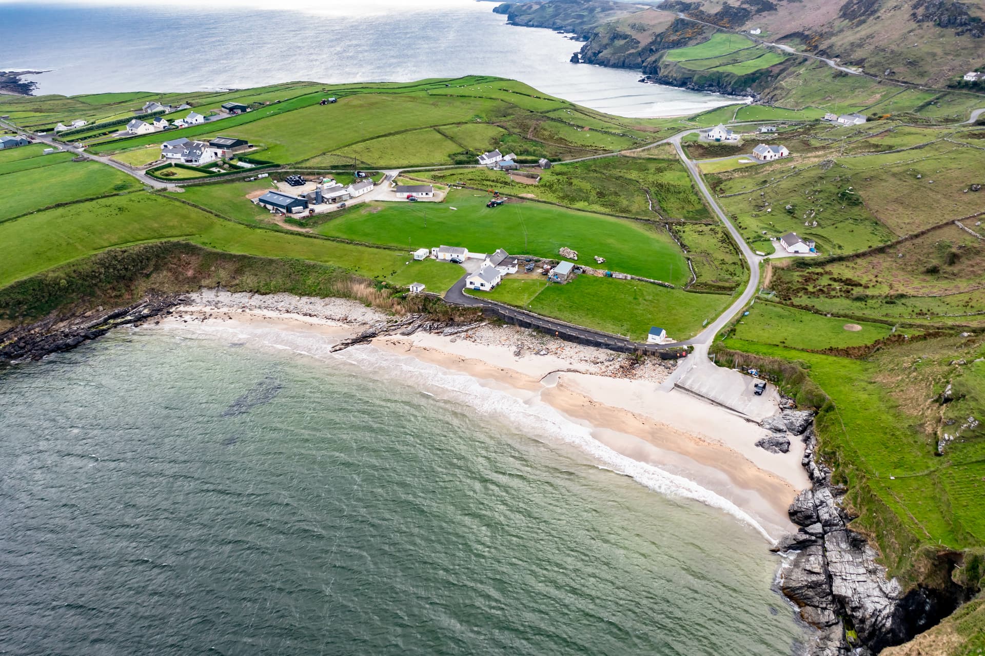 Coastal view of Muckros Head with green fields, white houses, and a sandy beach on the way to Carrick.