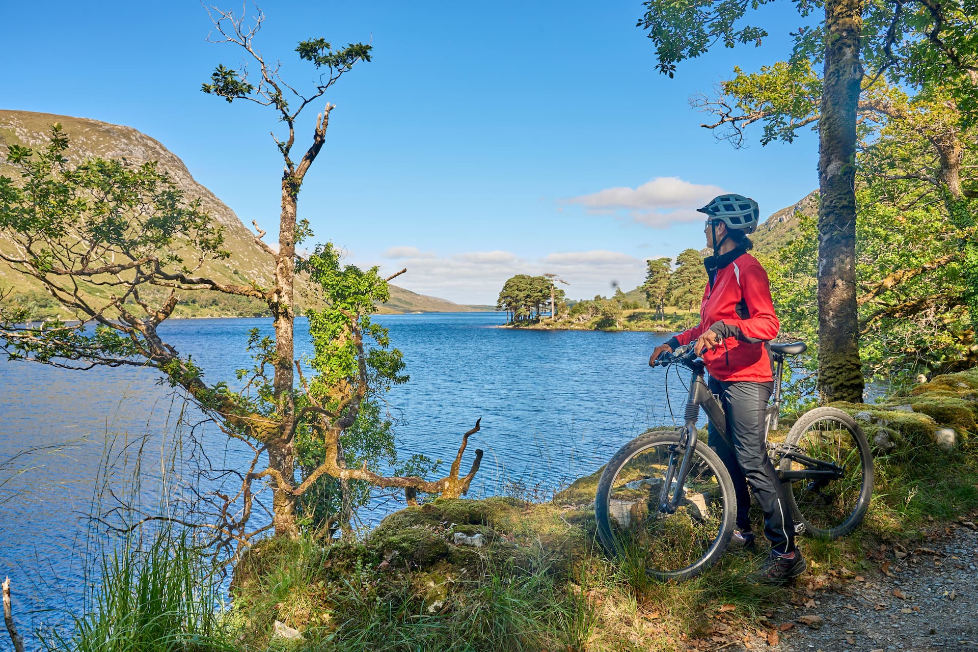 Cyclist with bike overlooking lake and mountains in Glenveagh National Park.