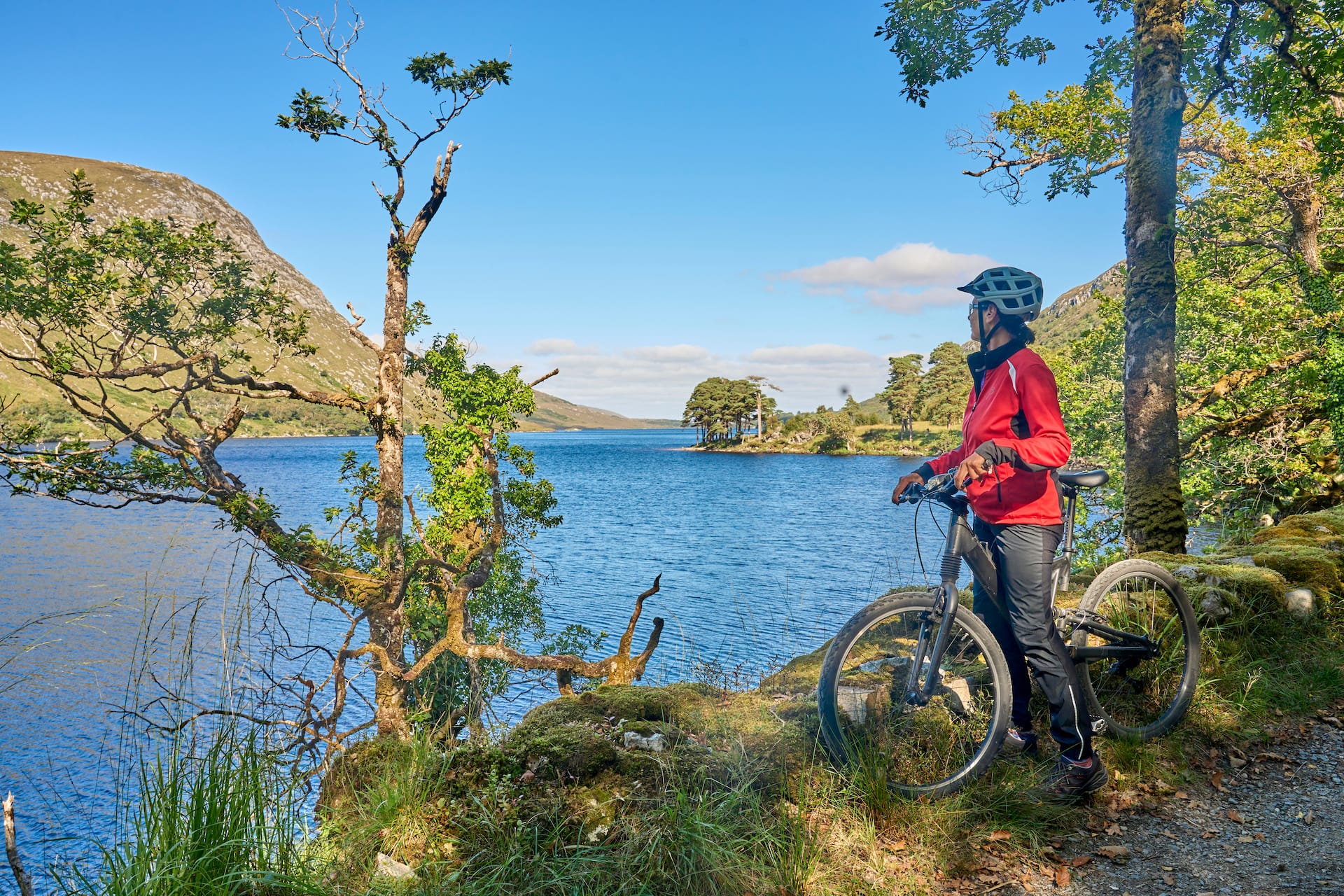 Cyclist with bike overlooking lake and mountains in Glenveagh National Park.