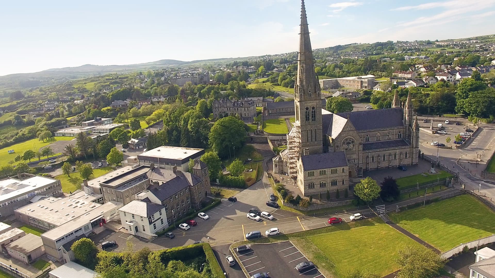 Aerial view of Letterkenny town showing a large stone church with a tall spire and surrounding green hills.