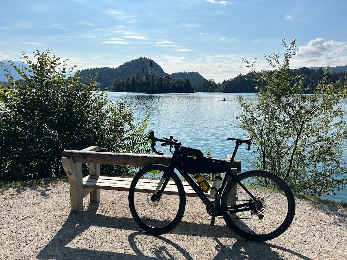 Bicycle parked by bench overlooking Lake Bled with island church and mountains